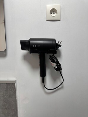 Ein schwarzer Föhn mit Kabel, eingesteckt in eine Steckdose.