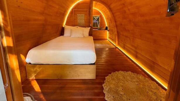 A wooden interior with a bed, a small table, and a wall-mounted light fixture. - Glicinia Boutique Hotel (Pacos De Ferreira)