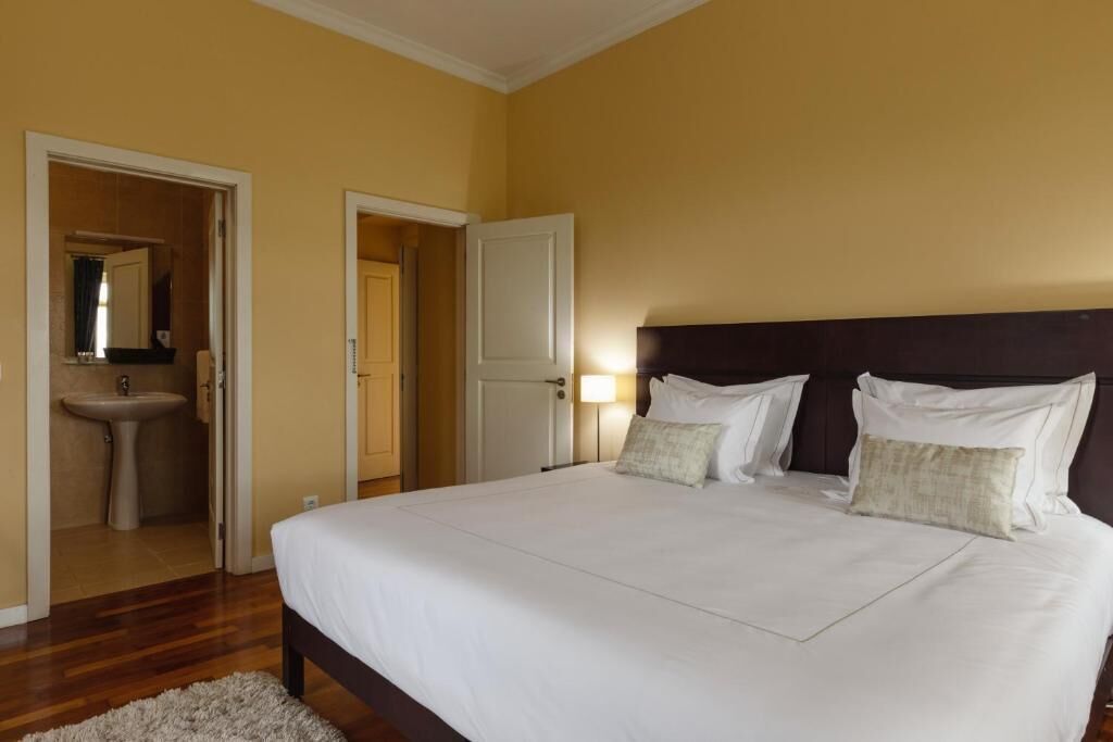 A bedroom with a large bed, a bedside table, a nightstand, and a mirror.