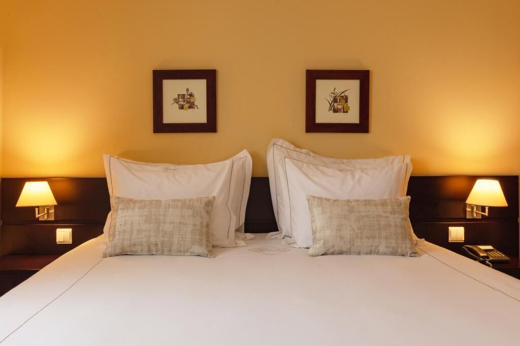 A double bed with two nightstands, each with a lamp and a phone.