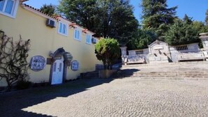 A cobblestone courtyard with a yellow building, a staircase, and trees. - Glicinia Boutique Hotel (Pacos De Ferreira)