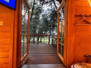 Uma cabana de madeira com uma porta de vidro que dá para um alpendre.