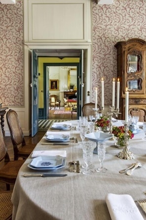 A dining table set with plates, glasses, and cutlery, with a vase of flowers and candles. - Le Château de la Villedubois, une propriété d’exception proposée par laclefduchateau.com, vous accueille près de Rennes pour un séjour de charme au cœur de la Bretagne. (Mordelles)