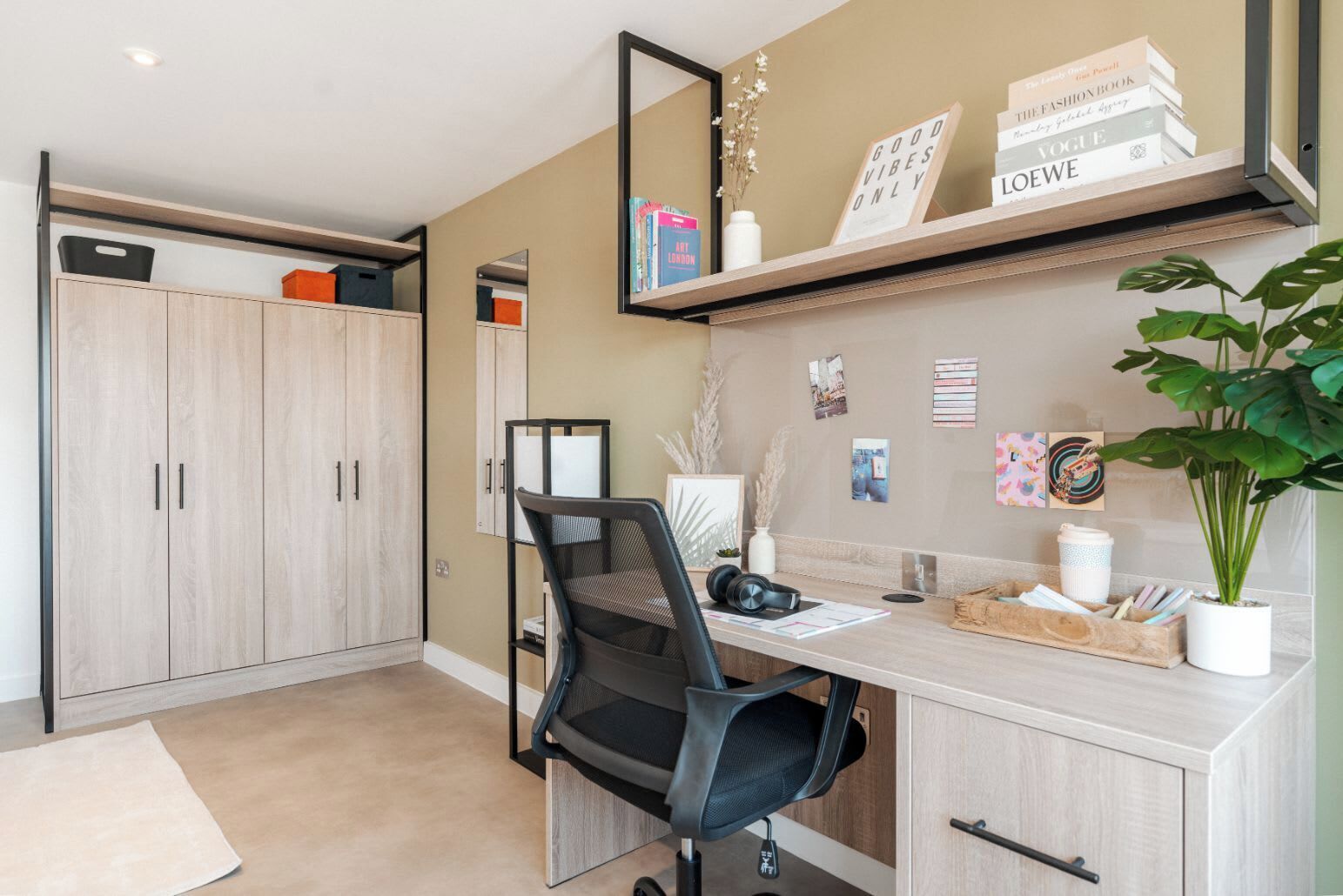 A modern office space with a desk, chair, shelving with books, and a potted plant.