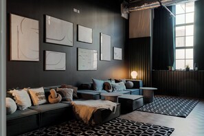 A modern living room with a sofa, coffee table, and patterned rugs. - Student Only YourTRIBE Deptford (London)