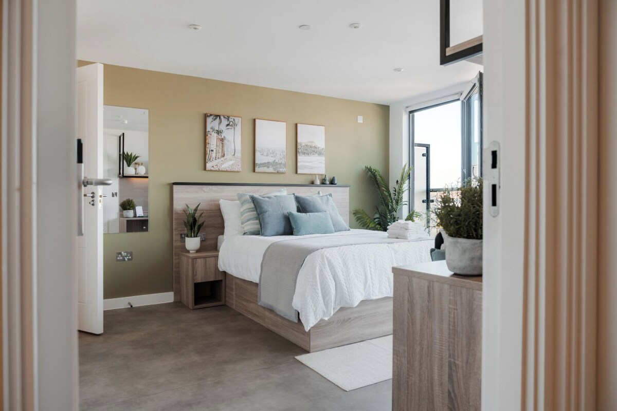 A modern bedroom with a bed, bedside tables, a dresser, and artwork on the wall.