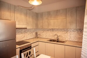 A modern kitchen with marble countertops, stainless steel appliances, and a built-in oven. - Perla Apartment 02 in Plazhi San Pietro (Plazhi San Pietro)