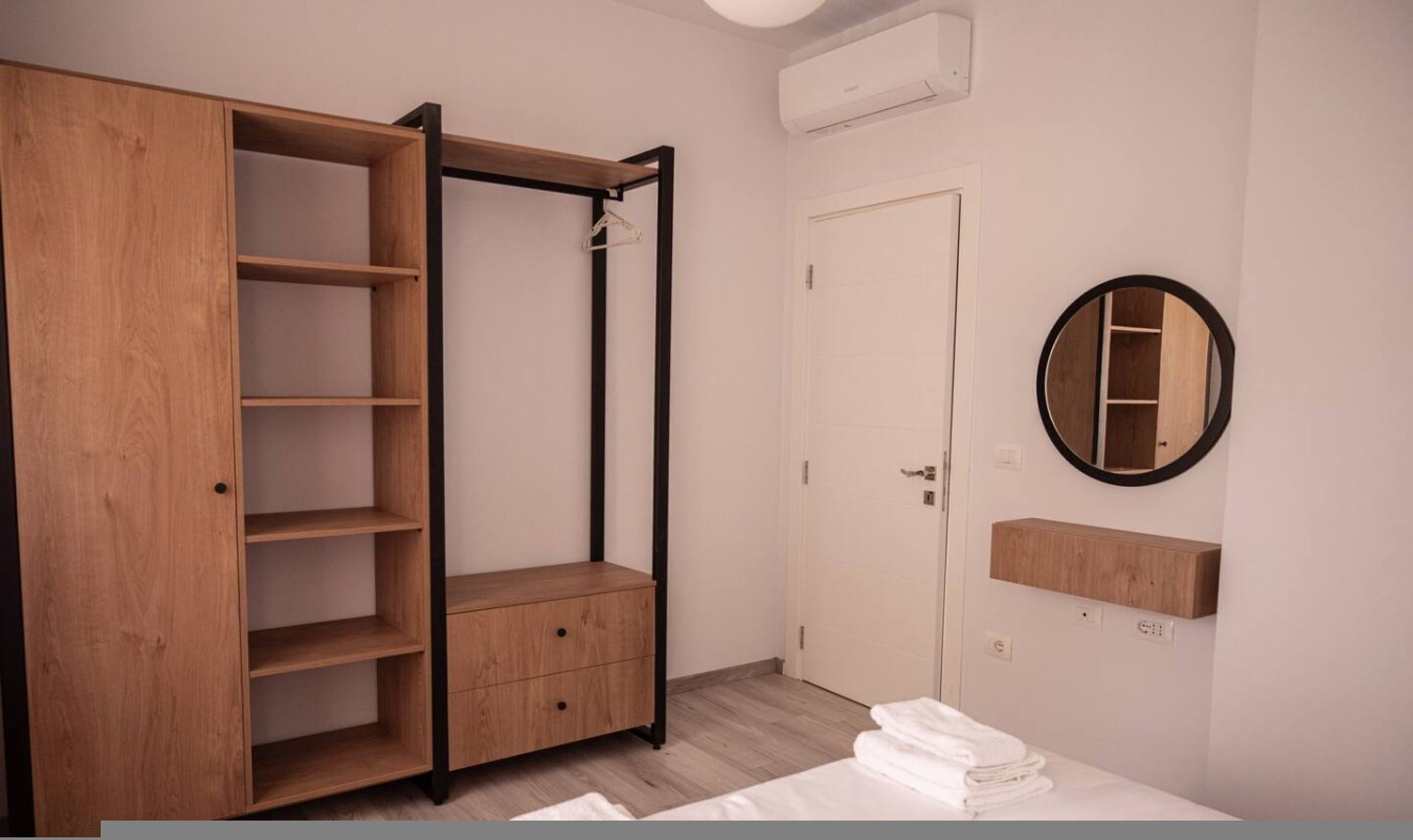 Une chambre avec une armoire, un lit, un miroir et un appareil de climatisation.