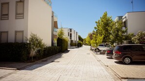 Een woonstraat met moderne gebouwen, geparkeerde auto's en een heldere lucht.