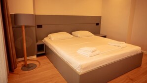 A neatly made bed with pillows and folded towels, a bedside lamp, and a small bedside table. - Villa with Pool | San Pietro Resort (Durrës)