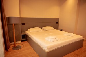 A neatly made bed with pillows and folded towels, a bedside lamp, and a small bedside table. - Villa with Pool | San Pietro Resort (Durrës)