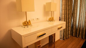 Een wit bureau met twee lampen, een gouden decoratie en een lade.