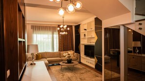 Een moderne woonkamer met een bank, salontafel en televisie. Een trap leidt naar een ander niveau.