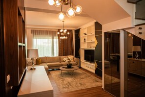 Ein modernes Wohnzimmer mit einer Couch, einem Couchtisch und einem Fernseher. Eine Treppe führt zu einer weiteren Ebene.