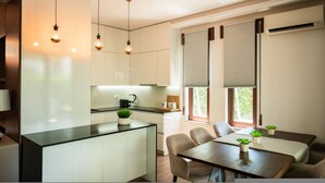 Een moderne keuken met een centraal eiland, hanglampen en een eethoek met een tafel en stoelen.