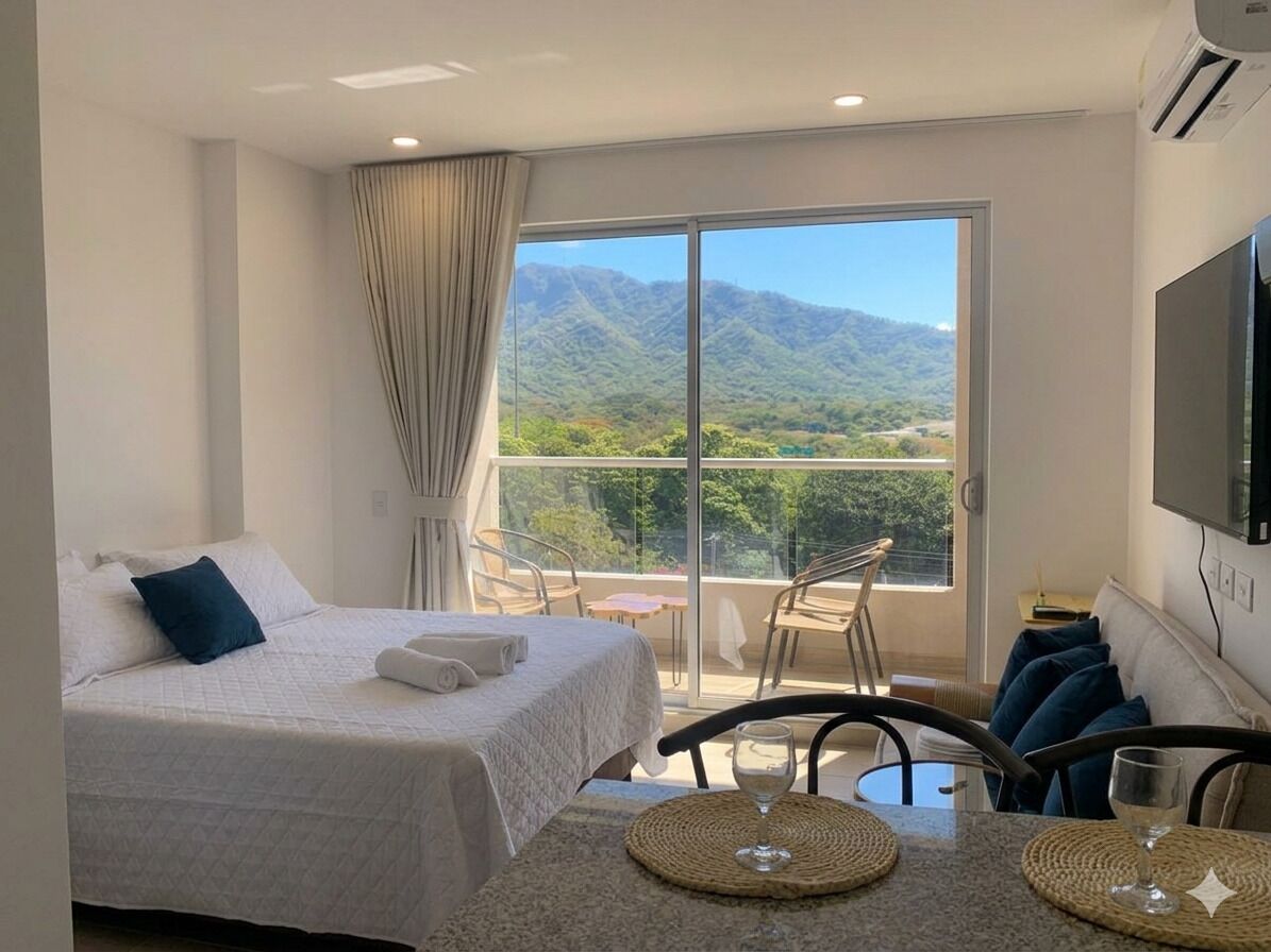 Quarto de hotel com cama, mesa de jantar, cadeiras, televisão e varanda com vista para as montanhas.