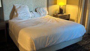 Ett hotellrum med en stor säng, ett nattduksbord med en lampa, en sänggavel och en tavla på väggen.