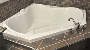 Ett badrum med ett fristående badkar, en dusch och ett kaklat golv.