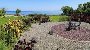 A garden with a circular seating area, a gravel path, and a view of the sea. - Mayfly Cottage (Clonbur)
