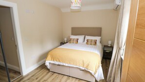 A bedroom with a bed, bedside tables, a lamp, a ceiling light, and a door. - Mayfly Cottage (Clonbur)