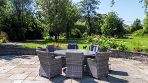 A patio with wicker furniture and a stone floor. - Mayfly Cottage (Clonbur)