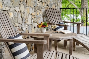 Espace extérieur aménagé avec des chaises et une table en bois, un vase rempli de fleurs et un verre de vin blanc.
