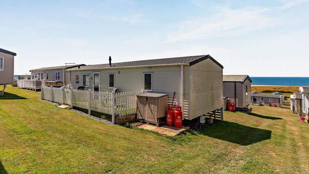 A mobile home with a fenced yard, a small shed, and two propane tanks.