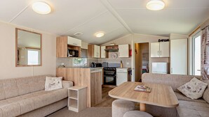 A compact living space with a kitchenette, a sofa, a coffee table, and a mirror.