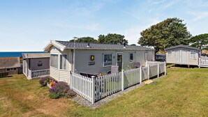 A mobile home with a fenced yard and a view of the sea.