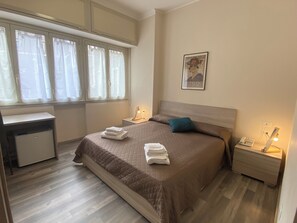 A bedroom with a bed, bedside tables, a desk, and a window with curtains. - R&B Santa Nicolella (Catania)