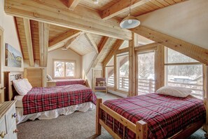 A bedroom with two beds, a wooden ceiling, and large windows. - Cook Family Lodge in Breckenridge (Breckenridge)