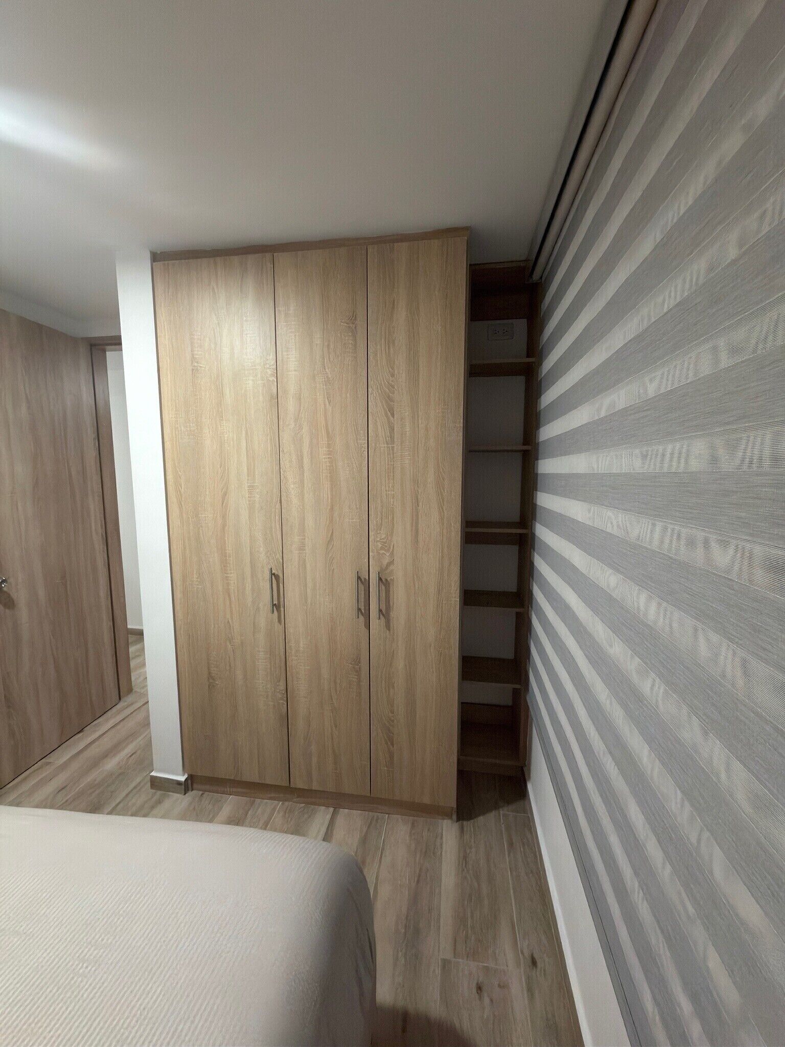 A bedroom with a large wardrobe, a bed, and a striped wall.