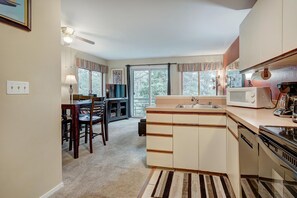 A compact kitchen with a dining area, a microwave, a dishwasher, and a large window. - Wildwood Suites 202 in Breckenridge (Breckenridge)