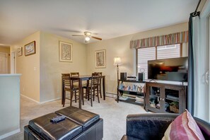 A living room with a TV, a ceiling fan, a dining table with chairs, and a bookshelf. - Wildwood Suites 202 in Breckenridge (Breckenridge)
