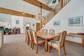 A spacious dining area with a wooden table and chairs, a staircase, and artwork on the walls. - Evan's Mountain Lodge (Blue River)