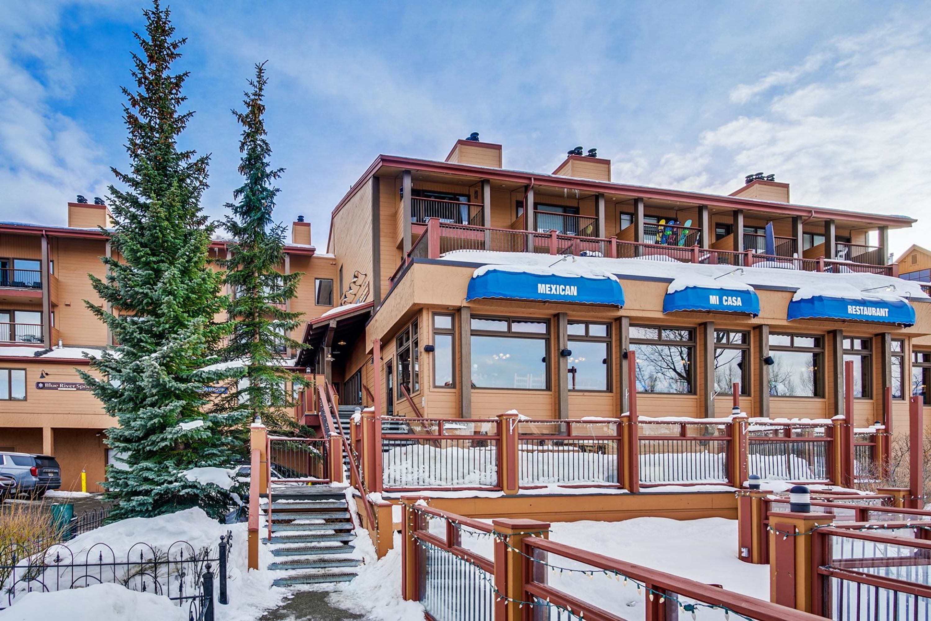 A hotel with multiple balconies, a staircase leading to the entrance, and a snow-covered ground.