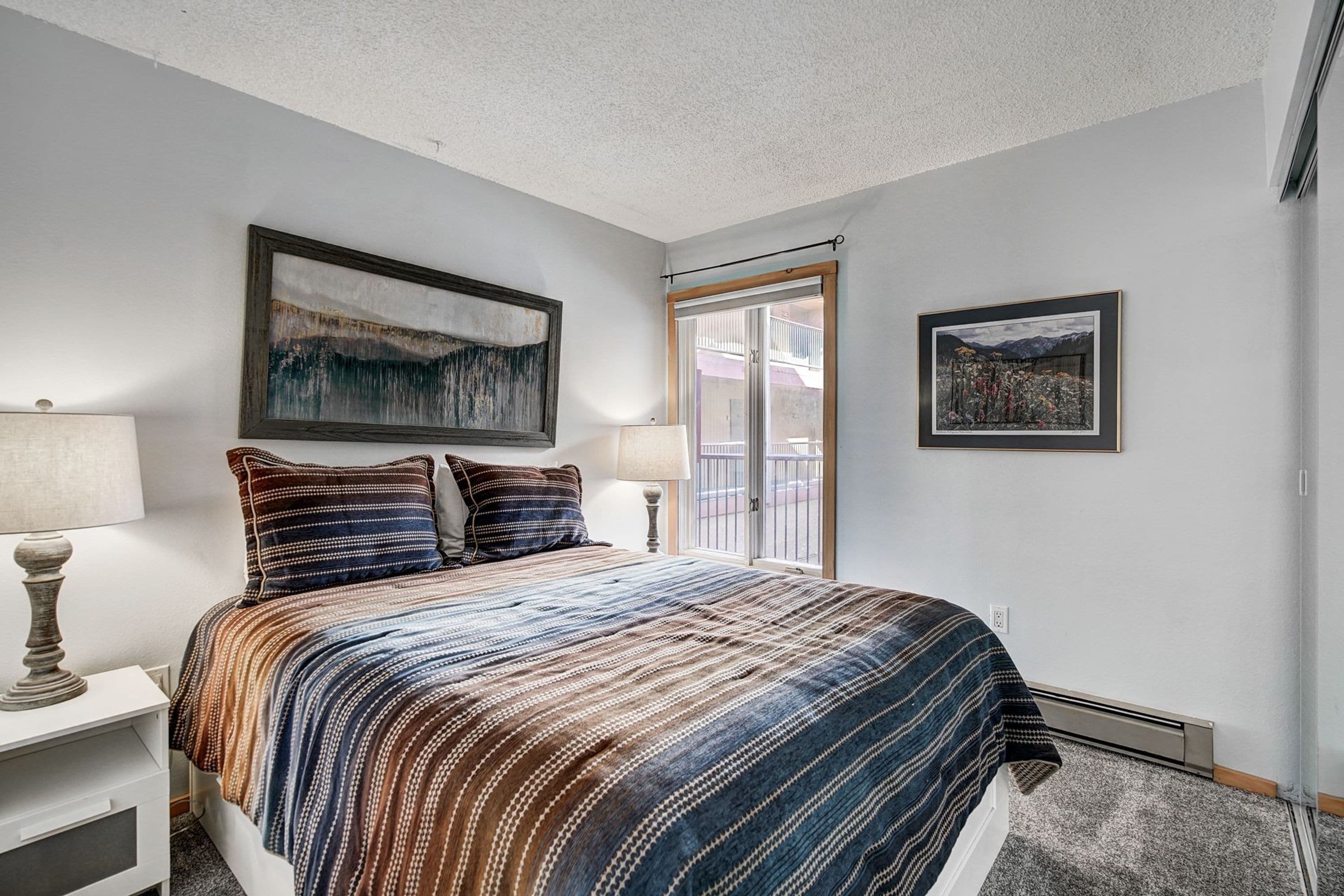 A bedroom with a bed, two bedside tables, a window, and two wall-mounted lamps.