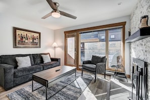A modern living room with a sofa, armchair, coffee table, and a painting of wine bottles. - Der Steiermark 104 in Breckenridge (Breckenridge)