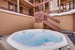 Ein Whirlpool in einer hölzernen Außenbereich mit einer Treppe, die zu einem Balkon führt.