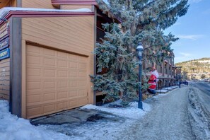 Una calle residencial con una puerta de garaje, un árbol cubierto de nieve y un paseo para peatones.