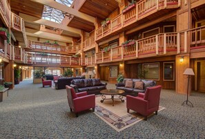 A spacious lobby with multiple seating areas, wooden balconies, and a high ceiling with skylights. - Atrium 104 in Breckenridge (Breckenridge)