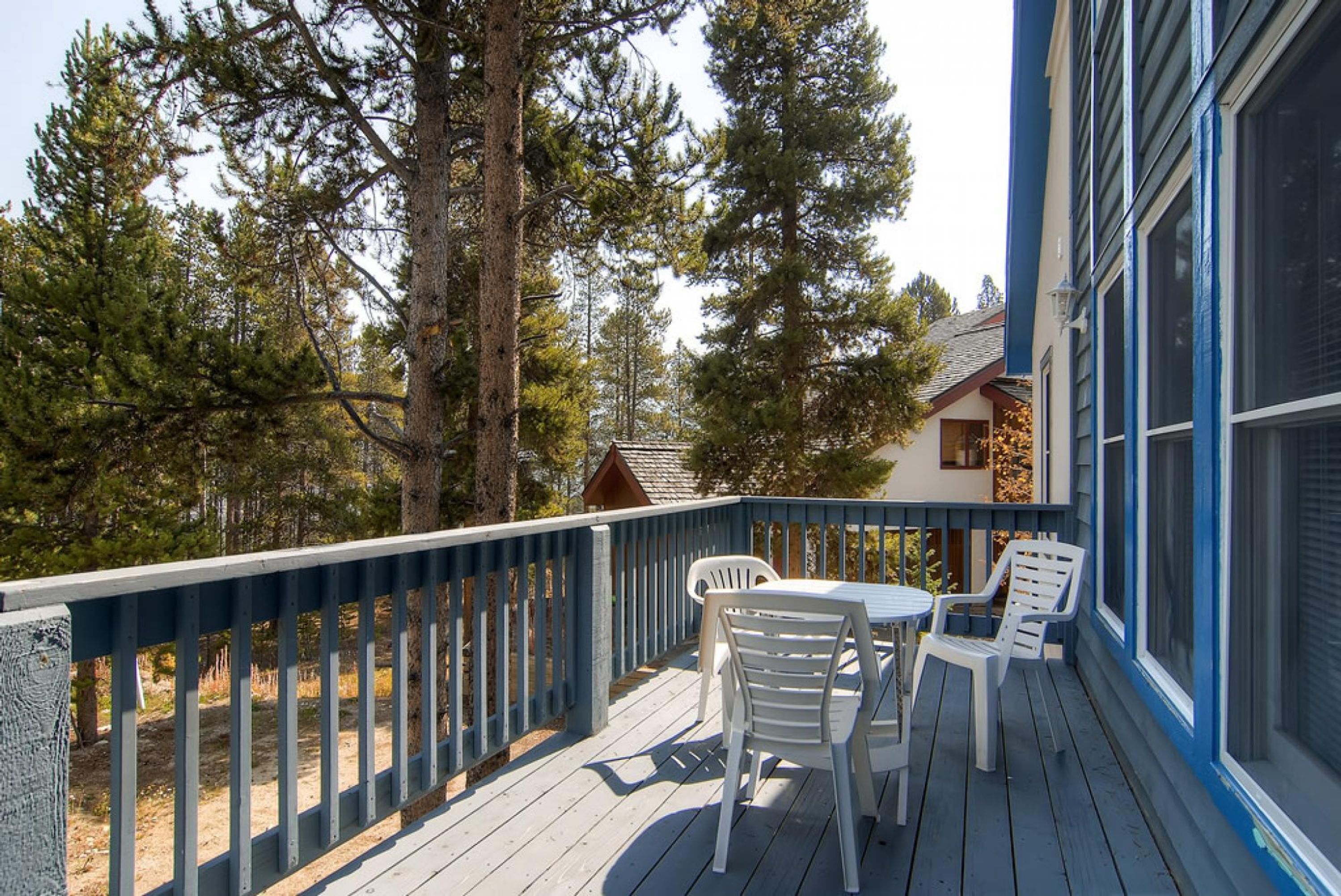 A wooden deck with a table and chairs, surrounded by trees.