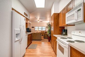 A compact kitchen with a refrigerator, microwave, stove, and a ceiling fan. - Casa De Alta in Breckenridge (Breckenridge)