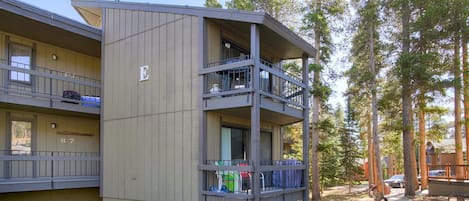 A multi-story building with balconies, a visible 'E' sign, and a pathway leading to a parked car.