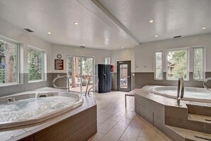 A spa area with two hot tubs, a wooden bench, and a door leading outside. - Gold Camp II E87 in Breckenridge (Breckenridge)