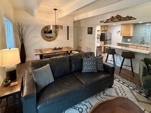 A modern living room with a leather sofa, a dining table, and a kitchen area with bar stools. - Columbine 108 in Breckenridge (Breckenridge)