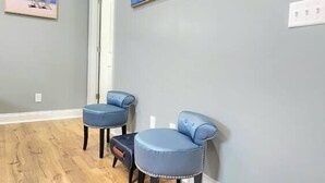 Un couloir avec un plancher en bois, un tableau représentant des voiliers et une porte.
