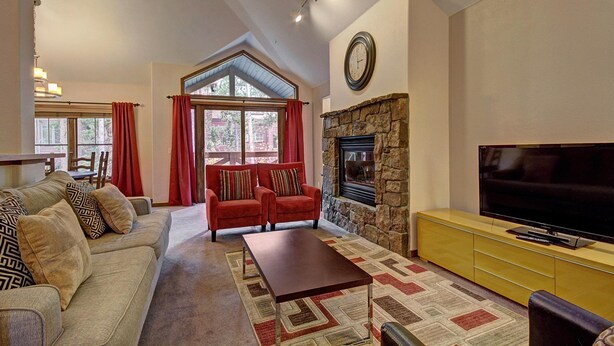 A living room with a sofa, armchairs, a coffee table, a fireplace, a television, and a dining area with a table and chairs. - Los Pinos D-24 in Breckenridge (Breckenridge)
