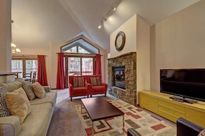 A living room with a sofa, armchairs, a coffee table, a fireplace, a television, and a dining area with a table and chairs. - Los Pinos D-24 in Breckenridge (Breckenridge)
