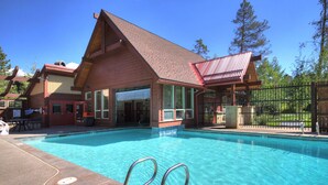 A pool area with a wooden building, a fenced area, and a clear blue pool. - Los Pinos D-24 in Breckenridge (Breckenridge)